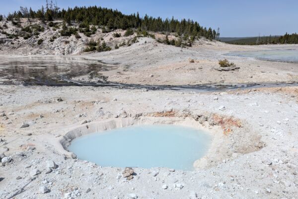 A new large cave discovered in Yellowstone National Park in the United States, now emitting turquoise spring water.